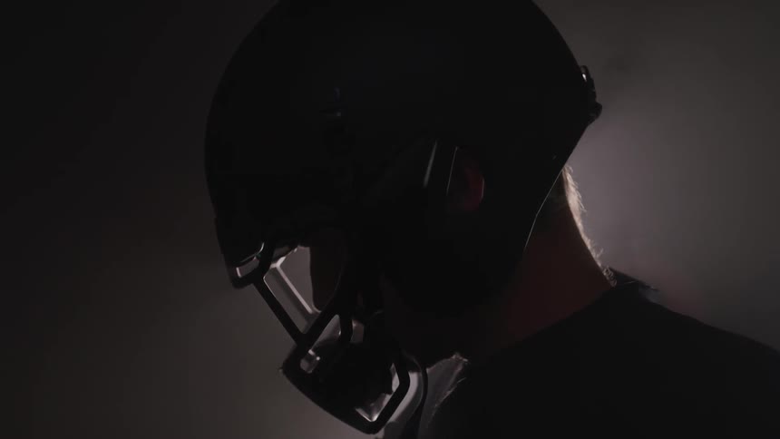 A man in a football helmet looks down