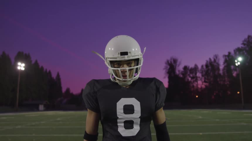 A man is wearing a football uniform and standing outdoors