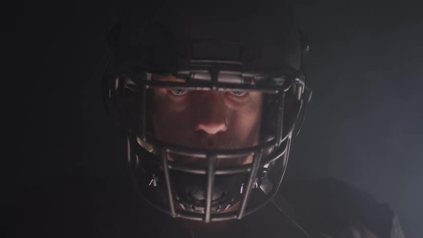 A mean wearing a football helmet stands in front of a light turning off and on