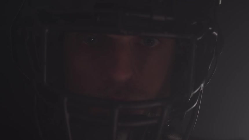 Man in football helmet stares as in shadows