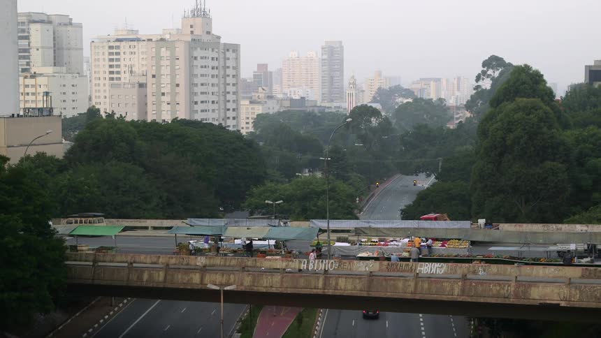 Wide shot of a street market on a highway overpass with the city skyline in the background