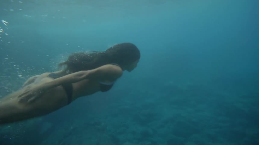 A woman in a bikini is swimming under water