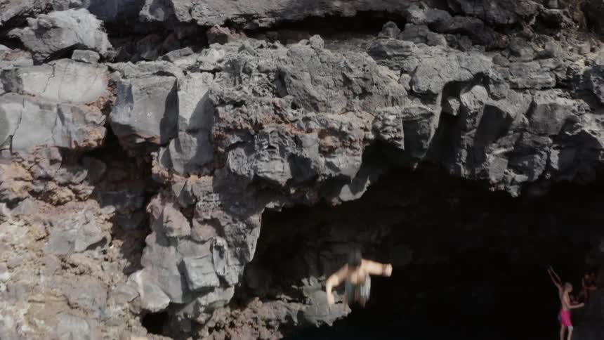 Two people jump off the cliff into the water