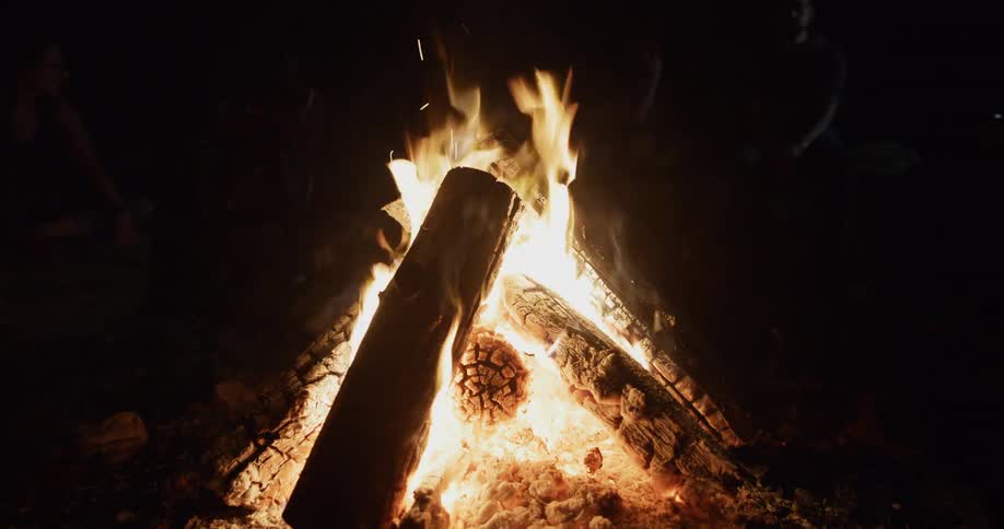 A campfire made from burning logs in the dark
