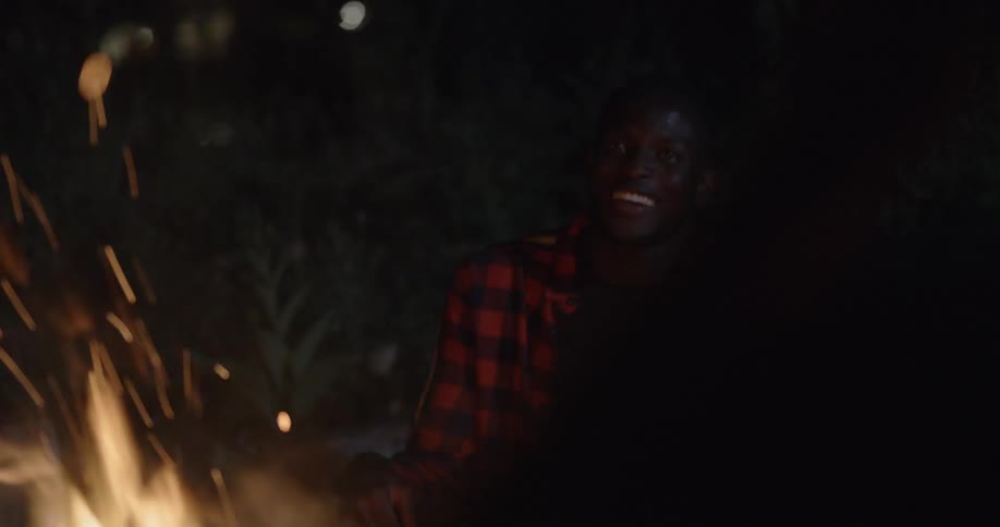 Friends sit and talk around bonfire