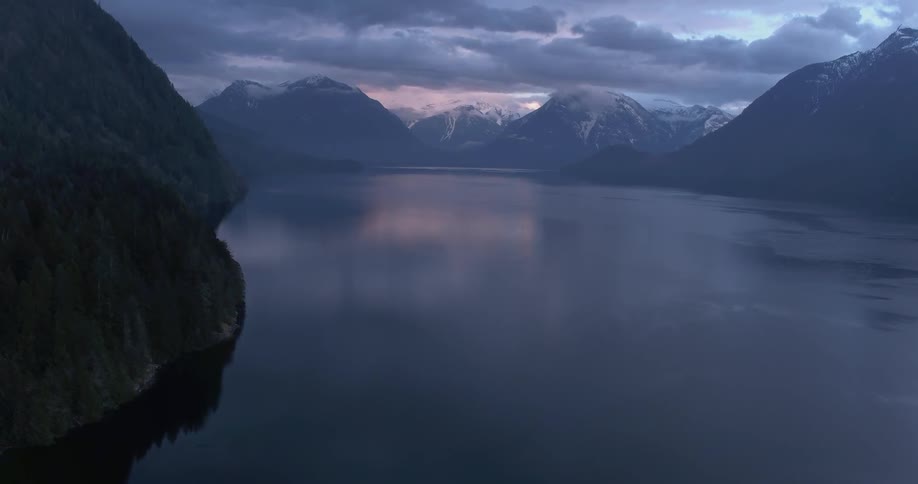 The river sits between the mountains under a cloudy sky