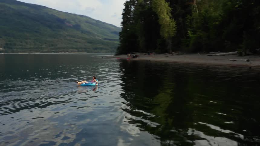 A woman is floating on a tube in the middle of a calm lake
