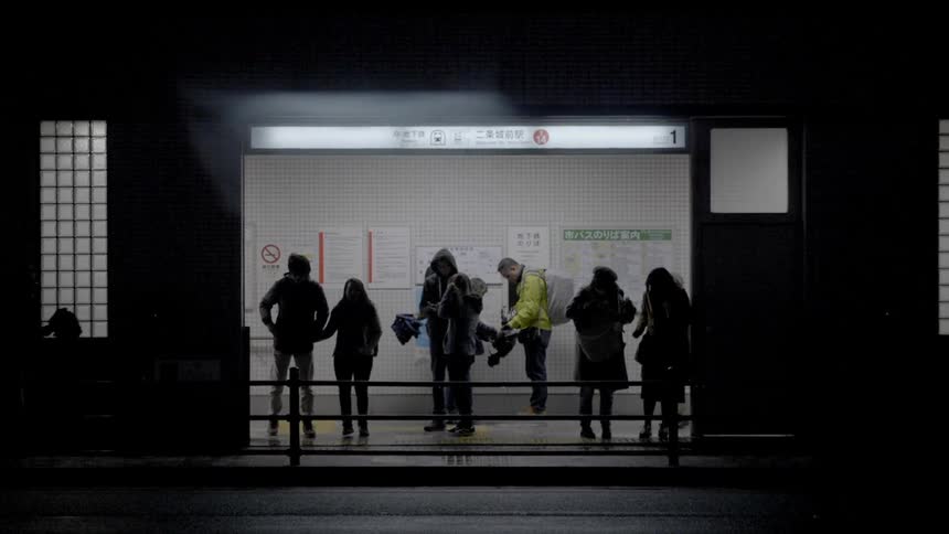Multiple people stand waiting for a subway to come down the tunnel