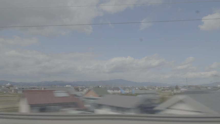 The view from a fast moving train by a suburban landscape