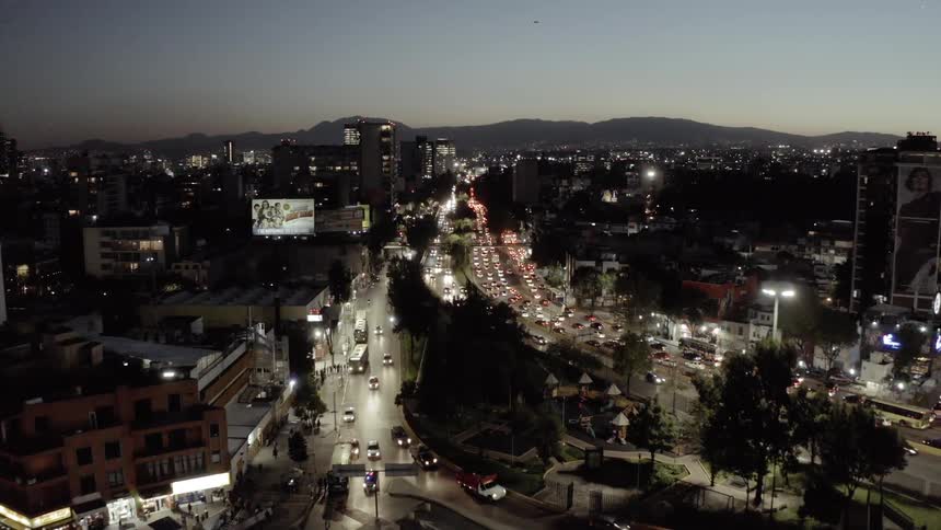 Traffic flows through a dense city at dusk
