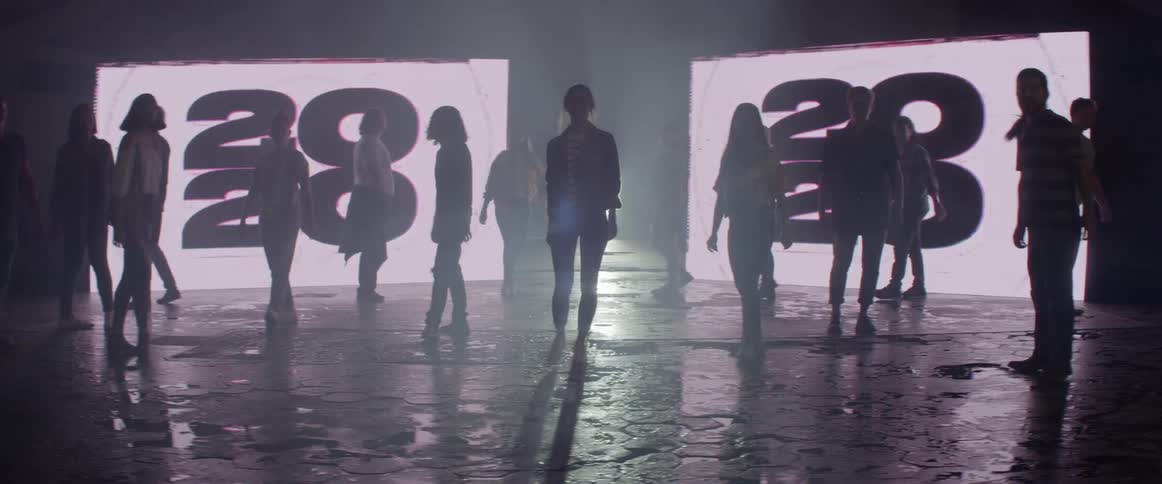 A group of people walk away from the large screens
