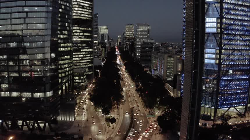 An aerial footage of a city skyline and road at night
