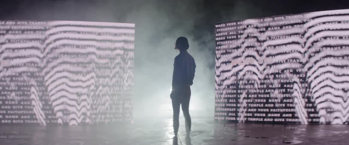 A silhouette of a woman in front of a screen