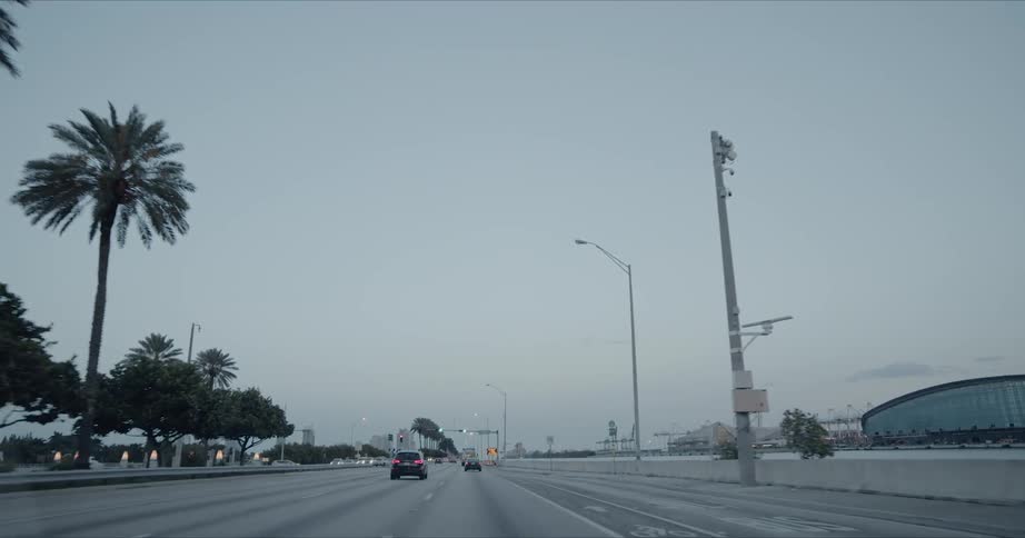 Several cars are driving along an expressway with several lanes for traffic