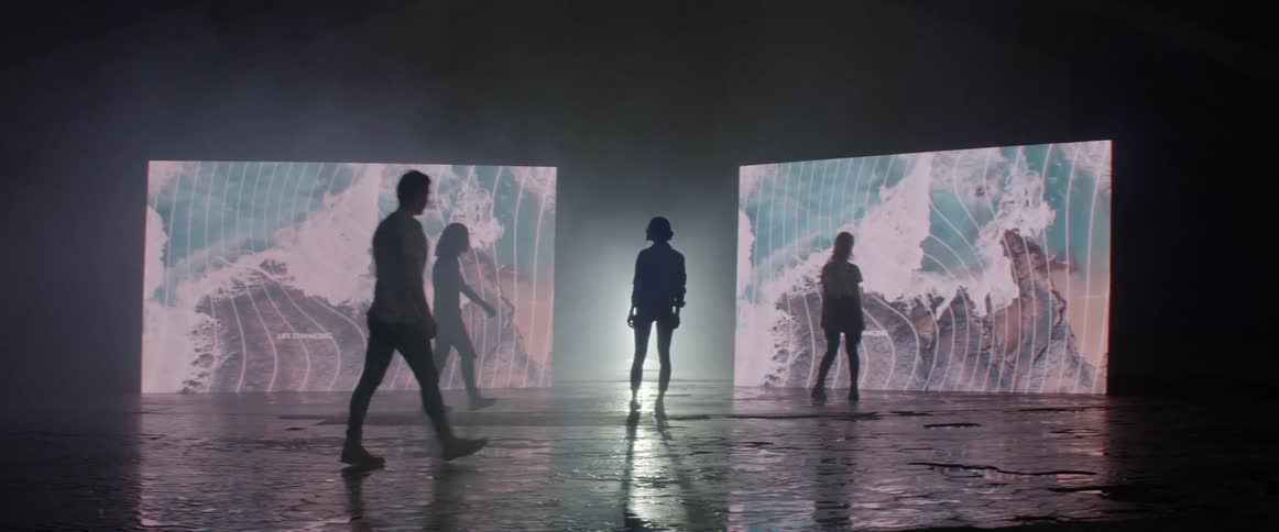People walking onto a stage with two screens in the background