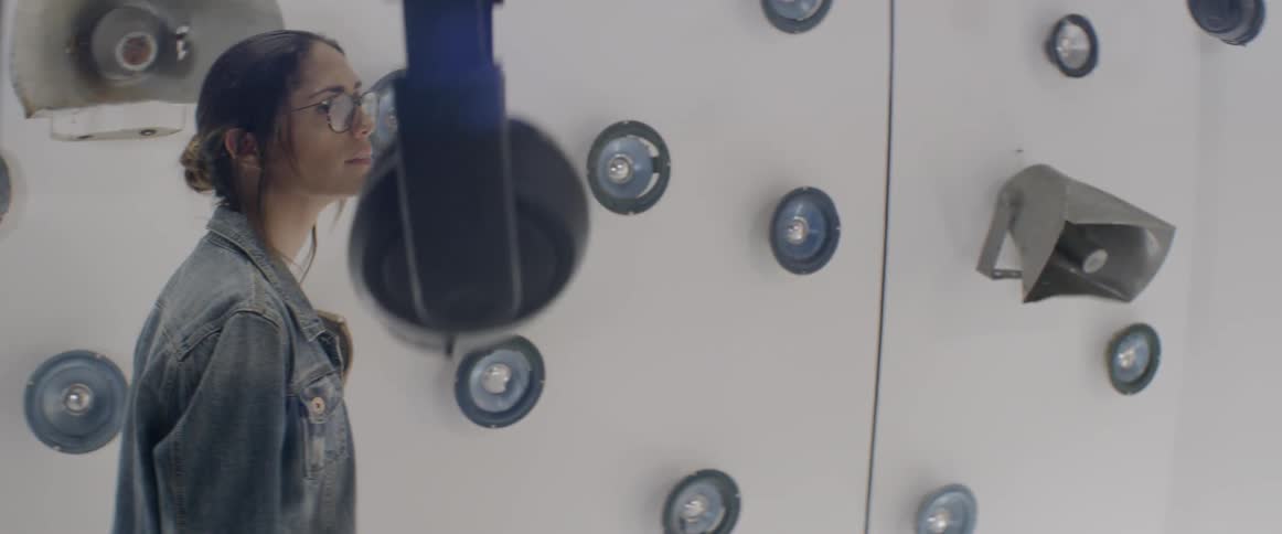 A series of speakers embedded into a wall with headphones hanging from the ceiling