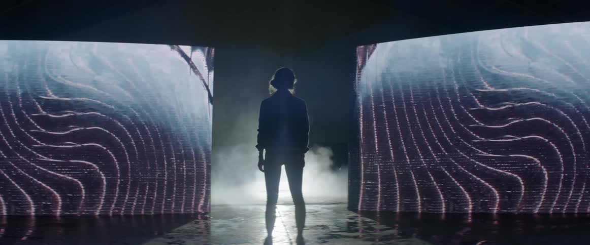 A woman is looking at huge screens that look futuristic
