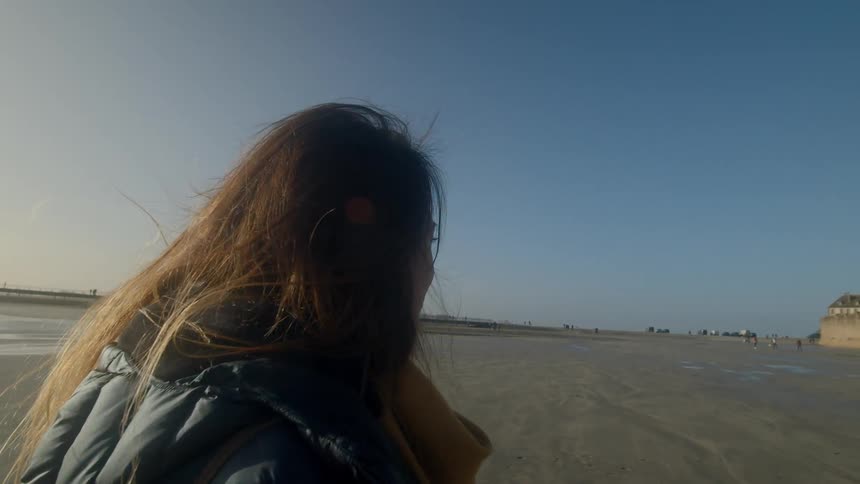 A woman near the shore with a fortress in the background
