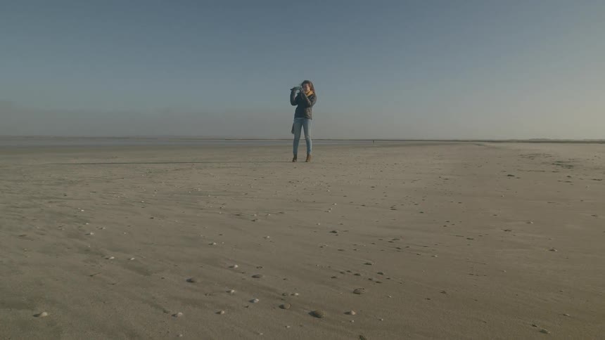 A woman taking a photo at the beach