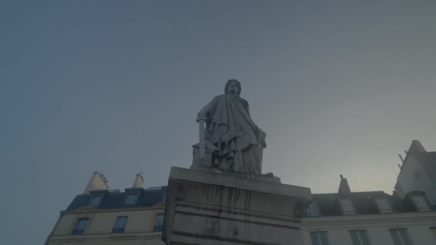 An old statue sits in front of a large building