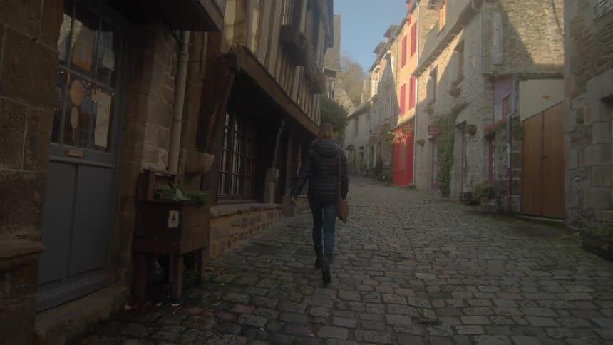 A woman walking down a stone road in an old european city