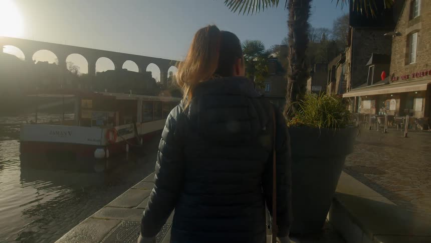 Woman strolls along on the promenade in the city at sunset