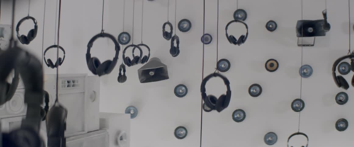 A room full of headphones hanging from the ceiling by strings