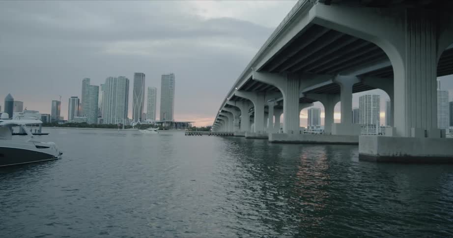 A wide bridge leading over a body of water into a city