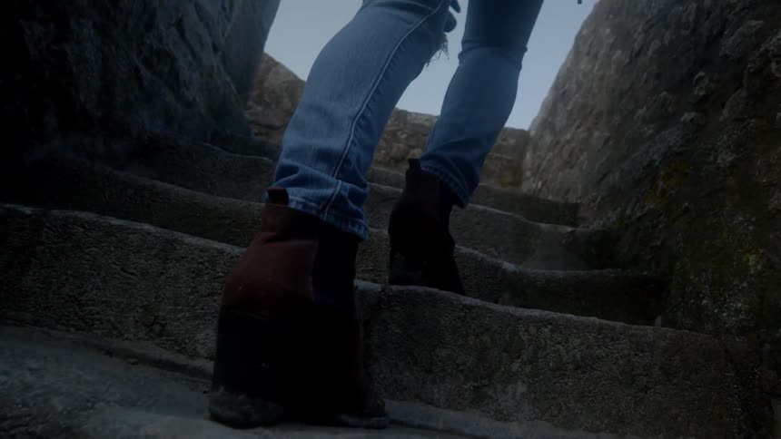 Female legs wearing booties and jeans climbing small narrow concrete steps