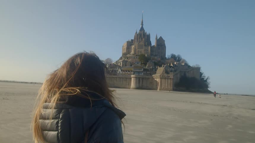 A woman standing in front of mont saint michel