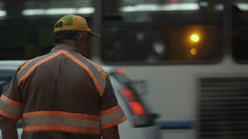 A man wearing safety clothing watches and directs traffic