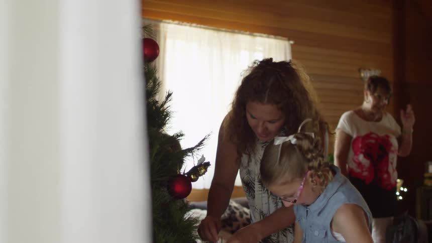 A large family gathers for christmas, talking and decorating the tree