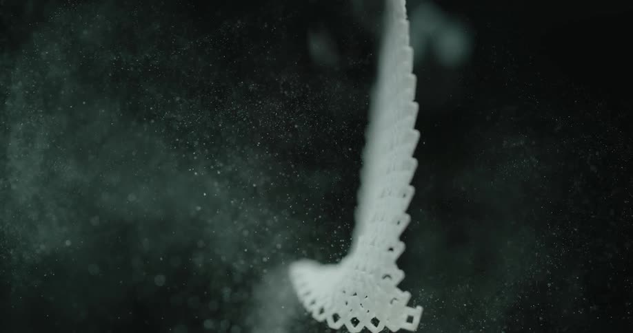 Small white mesh fabric piece spills dust into air as it sways