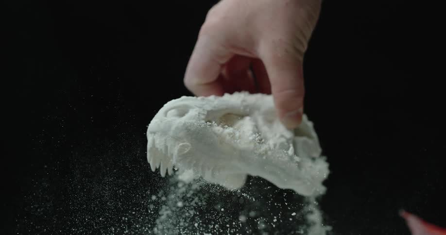 A mans hand shakes loose material off of a plaster mold