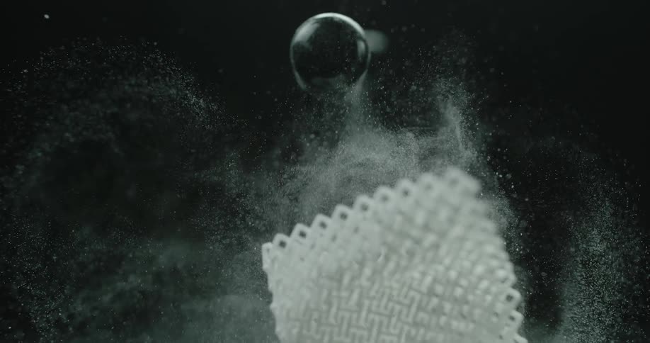 A cloth containing powder hits a spherical object discharging the powder from its stitching