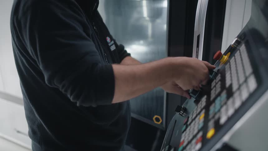A man turns dials on a large platform to control a machine beside him