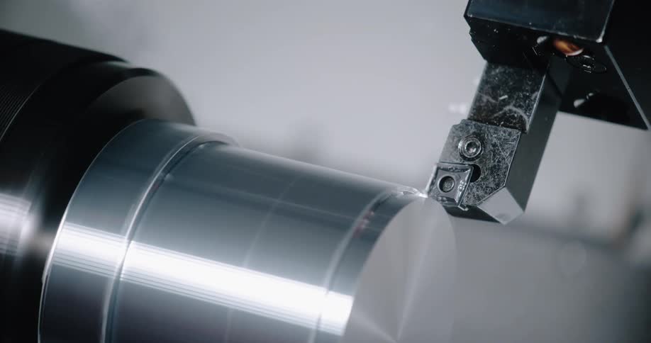 Metal shavings curl and fly up as a saw machine cuts and trims metal