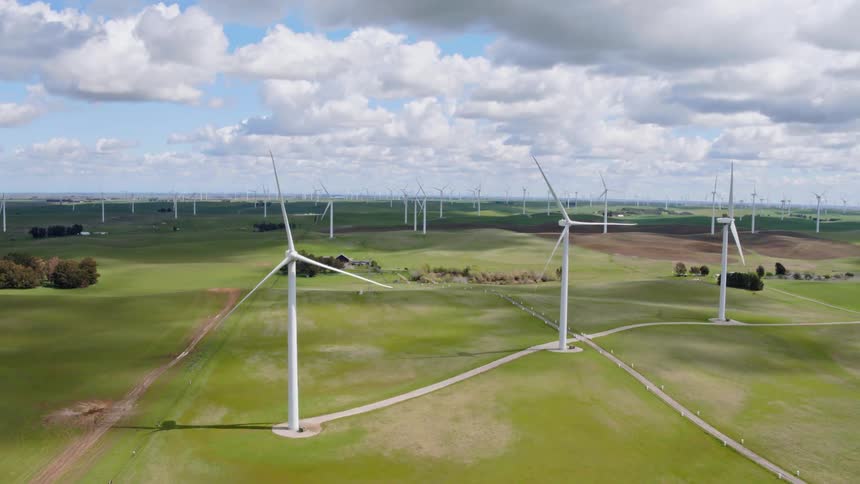 An aerial view of wind turbines in a rural field on a summer day