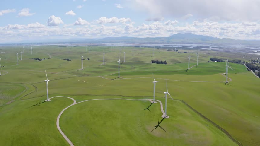 Several wind turbines are placed atop a wide open grassy plain