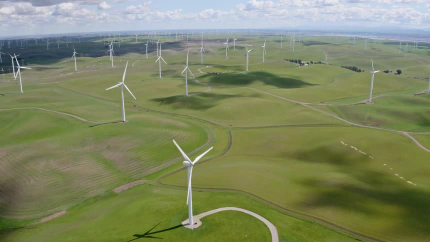 Windmills turn on a wind farm on flat grassland