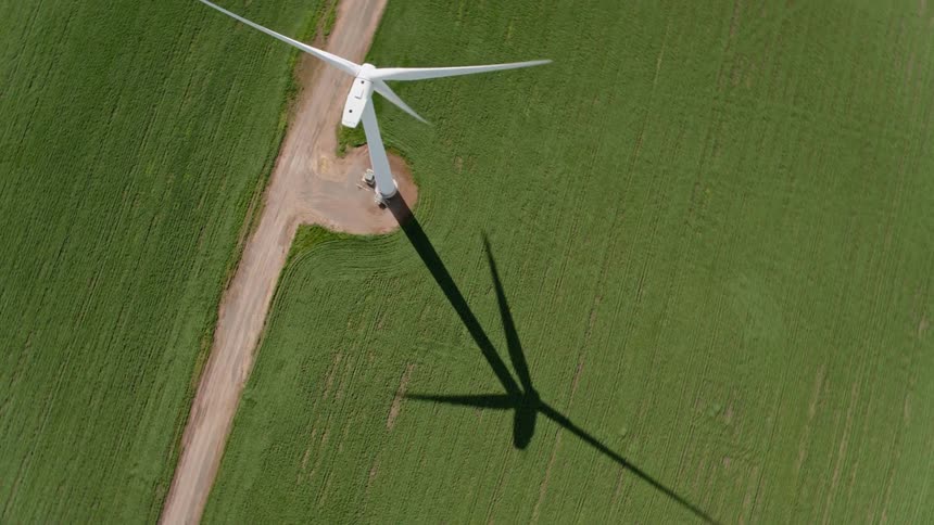 A single wind turbine cast a shadow on a smooth grassy field
