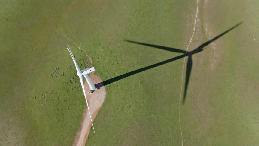 A wind turbine turns in the middle of a grassy field