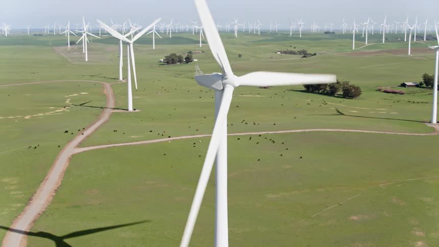 Dirt roads wind through a large wind turbine farm