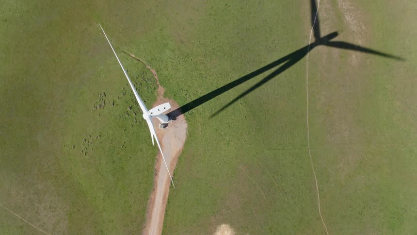 An aerial view of a wind turbine rotating in a rural field