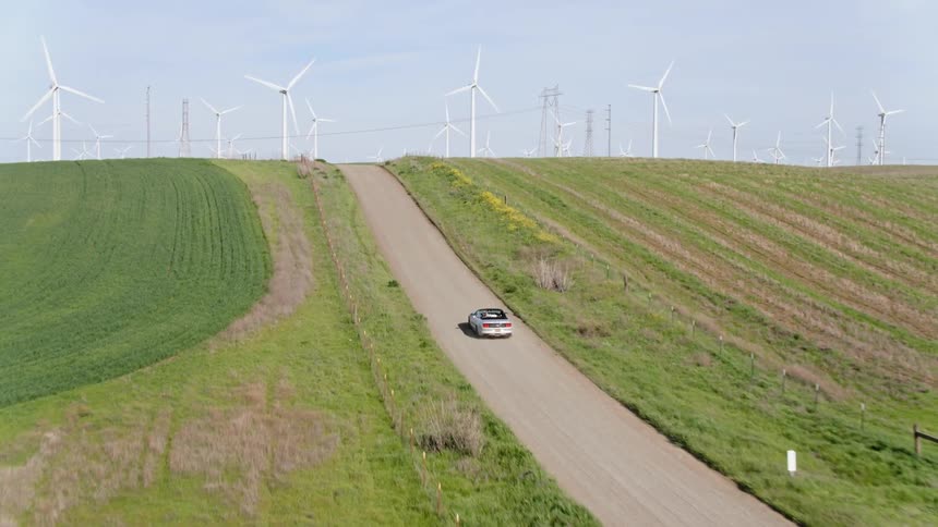 A car is driving on a road in a rural area