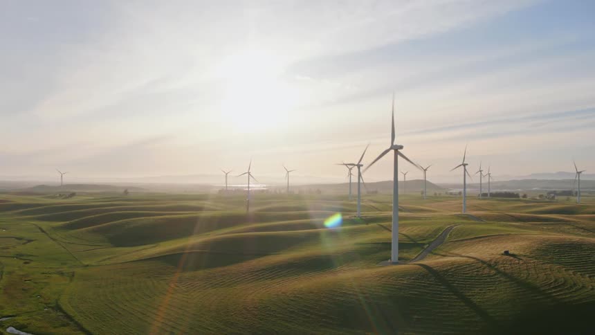 A wind farm stretches out and turbines spin the breeze