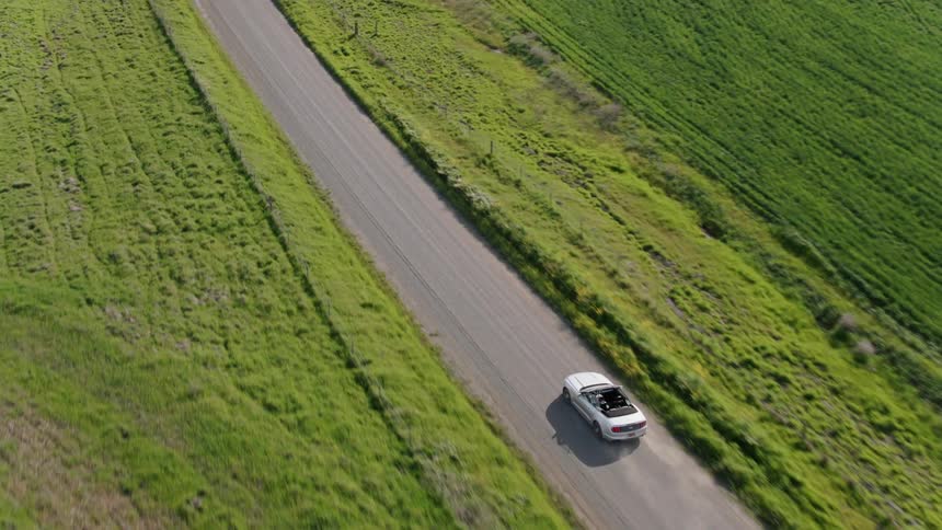 White convertible driving on a dirt road in the countryside