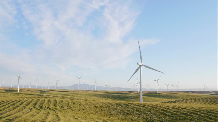Wind turbines spinning on green grass fields