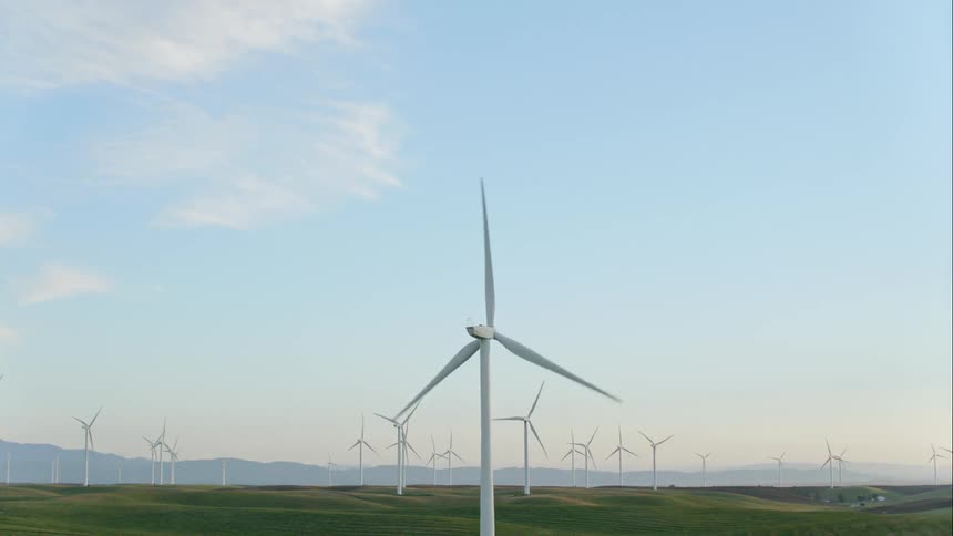 Wind turbines on wind farm with fog obscuring mountains on horizon