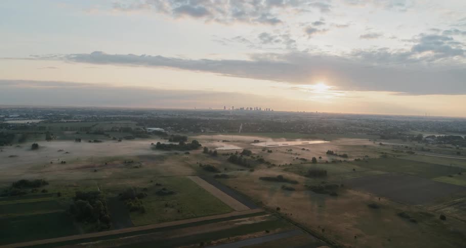 Far in the distance beyond abundant farmlands is a large metropolitan city